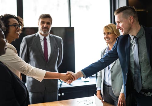 Professional people in business attire shaking hands in a well-lit room.